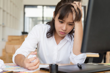 freelance graphic designer feeling stressful and has headache at office with digital tablet and color swatch catalog samples on desk