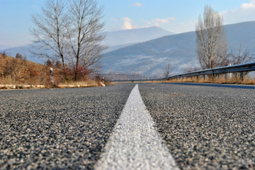Empty asphalt road with white line in the middle; asphalt road in the mointain on autumn day; selective focus.
