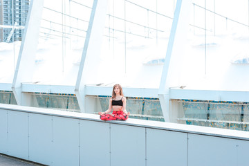 Woman doing yoga exercises outdoors in the city.Beautiful brunette fit young woman wearing sportswear practicing yoga urban style.Asana, fitness,sport,training and lifestyle concept