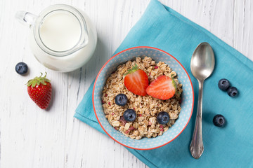 Healthy breakfast, bowl with granola muesli with strawberry and blueberry and milk jug, wooden...