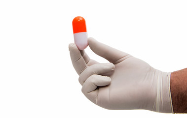 Hand holding a capsule or pill in medical gloves
