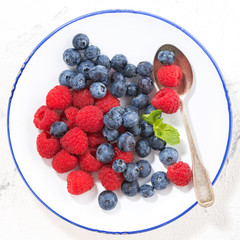 plate with fresh berries on a white background, top view