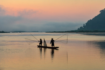 Silluate fisherman and boat in river on during sunrset,fisherman trowing the nets on during sunset,during sunset,Thailand