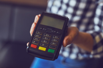 Close up of male hand holding payment terminal, toned