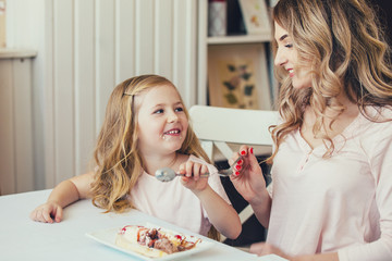 mother and daughter in a cafe sitting at a table and feed each other ice cream.Good relationship of parents and child. Happy moments together.