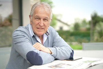 Senior man reading newspaper outside in yard