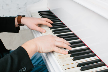 Fototapeta na wymiar Man's hands on keyboard of white piano