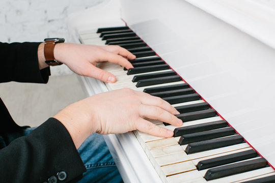 Man's hands on keyboard of white piano