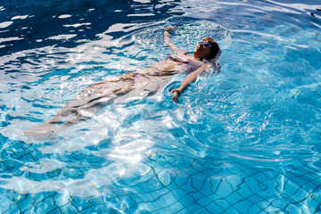 Brunette lies in outdoor pool