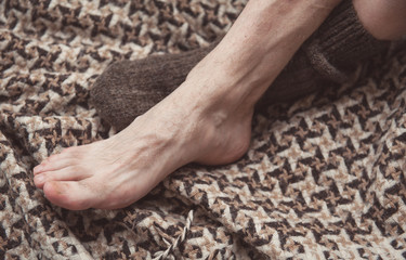 Man feet on woolen plaid in woolen sock. Cozy concept