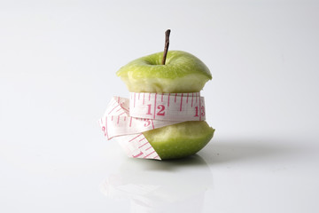 Close up of green apple with measuring tape isolated on white background.