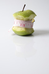 Close up of green apple with measuring tape isolated on white background.