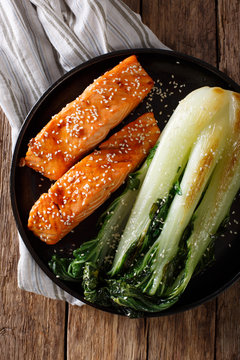 salmon in honey-soy glaze and fried bok choy close-up. Vertical top view