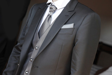 Dettaglio di abito da sposo sobrio ed elegante con evidenza di giacca, camicia, gilet e fiore...