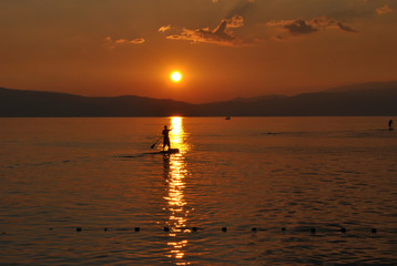 Naklejka na ściany i meble Stand up paddler silhouette on wonderful sunset; nature, sport and people concept.