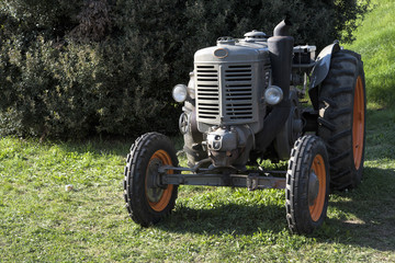  An old orange and green retro tractor in a field.