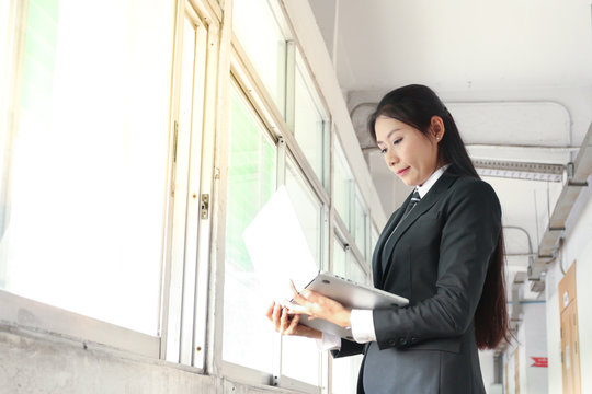 business woman in black suit and tie is looking at laptop on hands