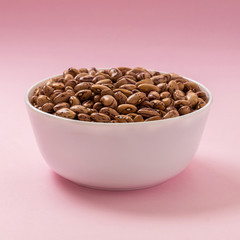Raw pinto bean in a bowl on pink background
