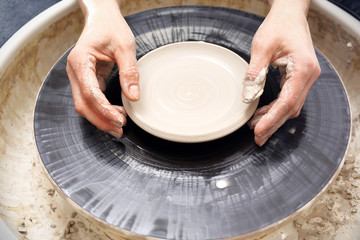Praca na kole garncarskim. Kobieta lepi naczynia z gliny na kole garncarskim.