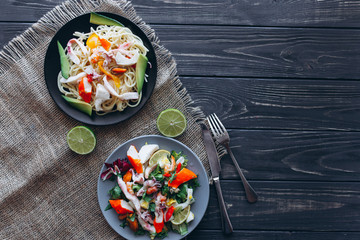 salad and pasta with seafood on wooden background