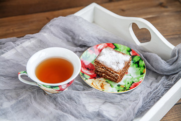 Delicious cake and a cup of hot tea on a white tray. The concept of food and dessert.