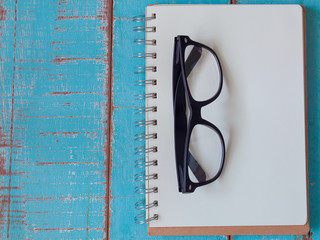 notebook and glasses  on wooden floor.