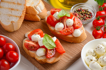 Bruschetta with cherry tomatoes and mozzarella on wooden board.