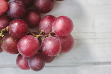 Red grapes over the white wooden board.