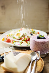 Chia blueberries smoothie and fresh salad with parmesan shavings falling on top of salad