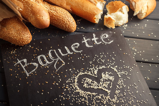 French baguettes with sesame seed on black wooden background