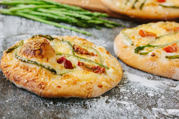 Mini pizza with asparagus. Traditional small pizza for personal eating filling with cheese, tomatoes and asparagus.