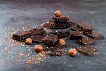 Dark chocolate pieces with nuts and cocoa  on dark  background.