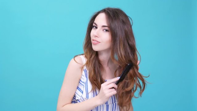 Young smiling brunette woman brushing her hair and winking isolated