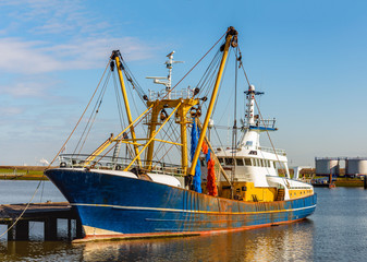 Fototapeta premium Rusty Dutch trawler moored at a wooden jetty