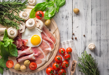 Healthy Mediterranean breakfast ingredients, ham, fried eggs, tomatoes