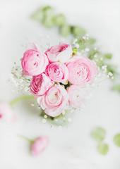 Light pink spring ranunkulus flowers bouquet on white marble background, top view, selective focus, copy space, vertical composition. Spring greeting card concept