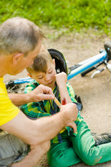 Father puts a bandage on a wound to his son, who fell off his bicycle