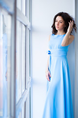 Fototapeta na wymiar Beautiful girl in a blue dress, spring,the girl at the window