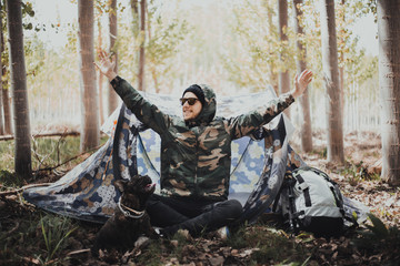 Man backpacker in the mountain with his camping tent and his French bulldog dog