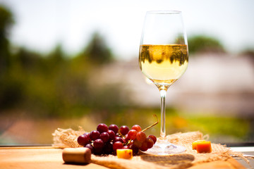 Grape, cheese with a glass of white wine on green blurred background
