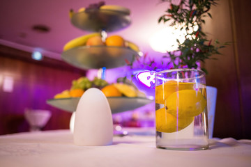Bright yellow lemons floating in a glass of water, Fruit tower on top of a table, Fruits on a table 