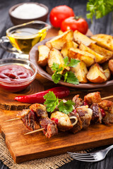 Meat skewer with herbs With onions, baked potatoes, tomatoes and greens