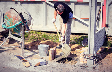 Pour concrete on the foundation of the fence with a mixer.