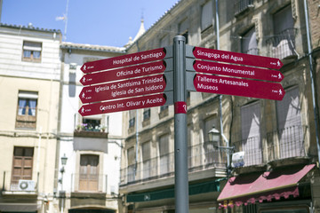 Street sign on street indicating City Center of Ubeda, set monumental, Cathedral, Hospital de Santiago,  Typical architecture in the background.