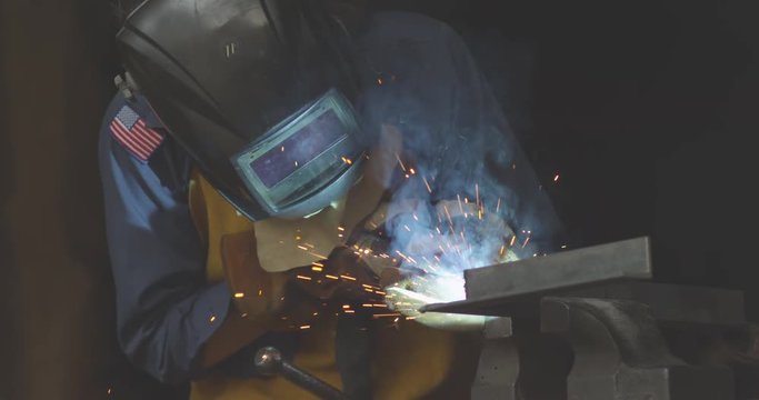  slow motion shot of a female worker using a welder at a metal shop. 