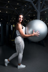 Fototapeta premium young girl with sexual inflated figure, in the gym holding a fitness ball
