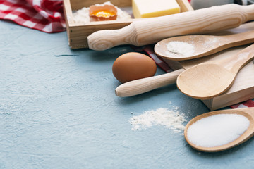 Baking cake in rural kitchen - dough recipe ingredients (eggs, flour, milk, butter, sugar) on white wooden table from above.