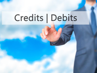 Credits  Debits - Businessman hand pressing button on touch screen interface.