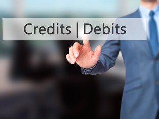 Credits  Debits - Businessman hand pressing button on touch screen interface.
