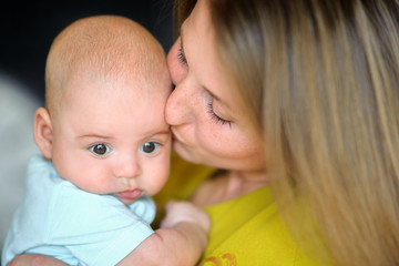 mother with tenderness and love holds on hands of the newborn baby, tenderly kisses